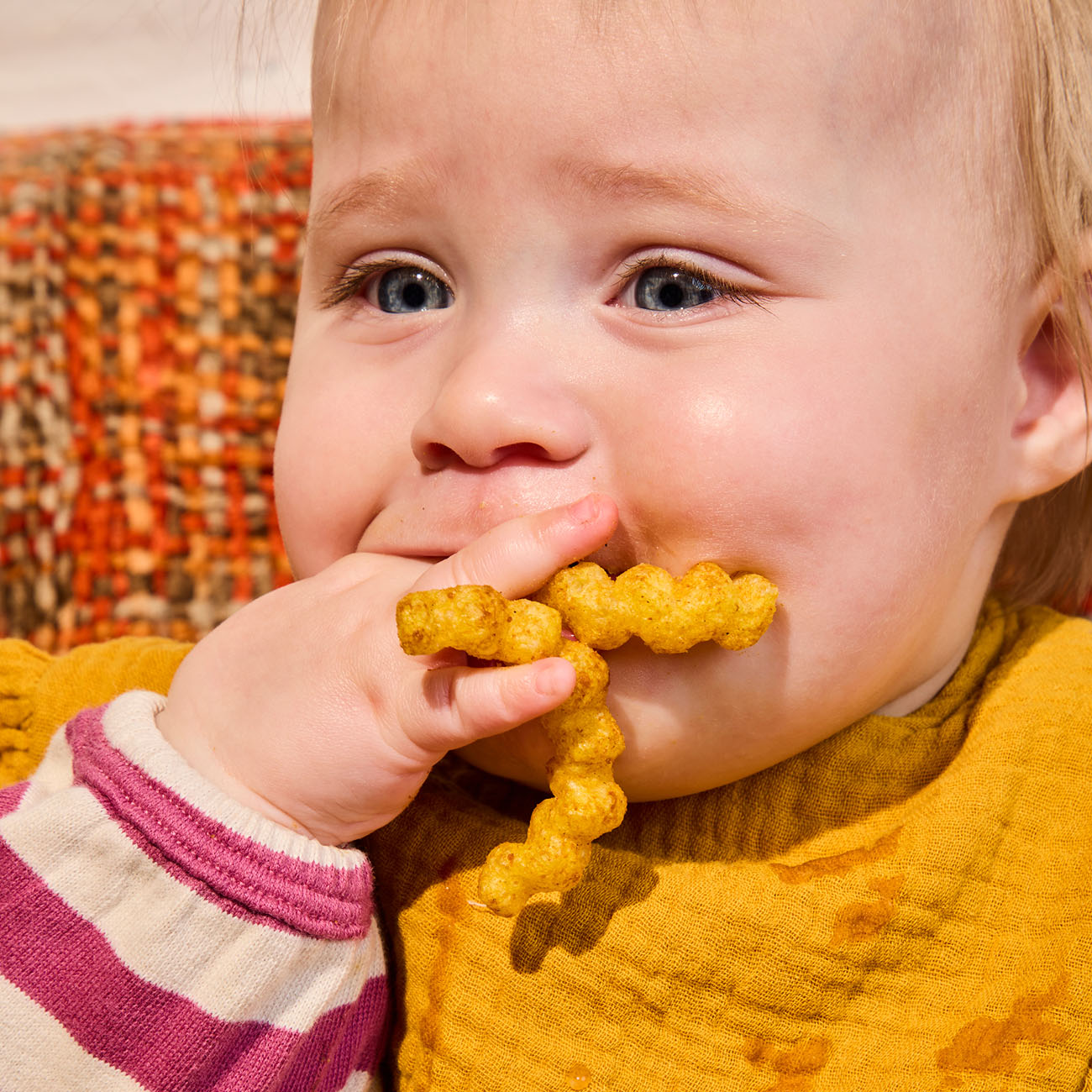 baby putting a handful of Pumpkin Pear Meltable Baby Crinkles in their mouth