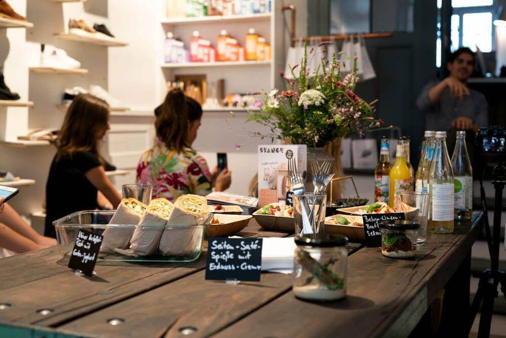 Teilnehmer hinter Tisch im LOVECO Vegan Shoes Laden in Berlin Kreuzberg