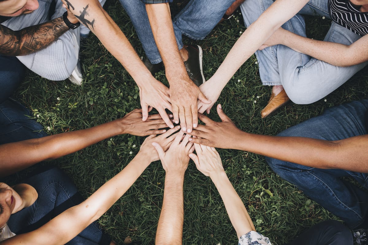 group of people placing hands together in a circle