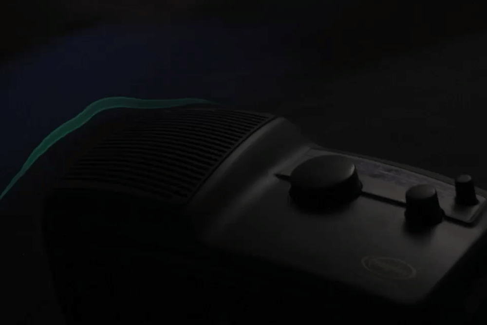 A photograph of green and red light above a dark photo of an electric radio. The red light gets bigger above the speaker