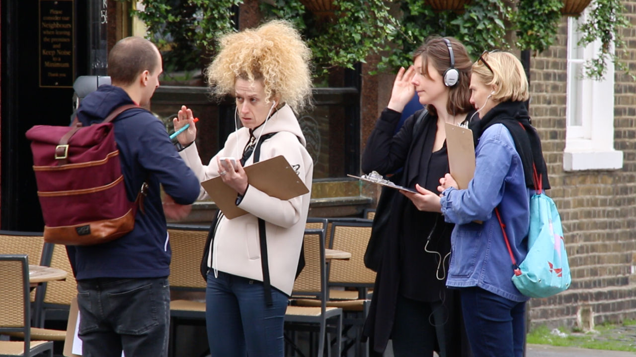 People standing on a street in London listening to a story in their headphones