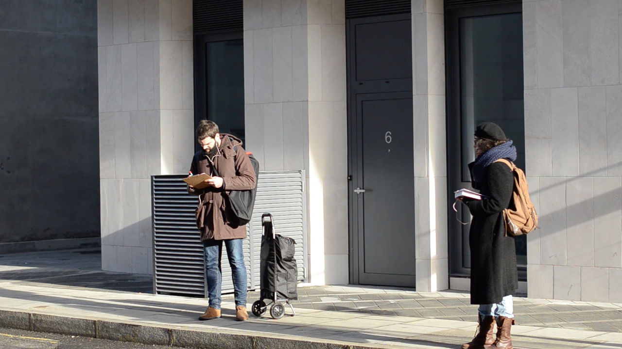 People standing on a street in London listening to a story in their headphones