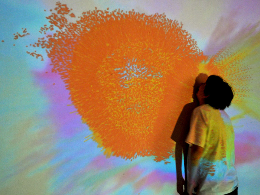 A child staring at a colourful projection on a white wall