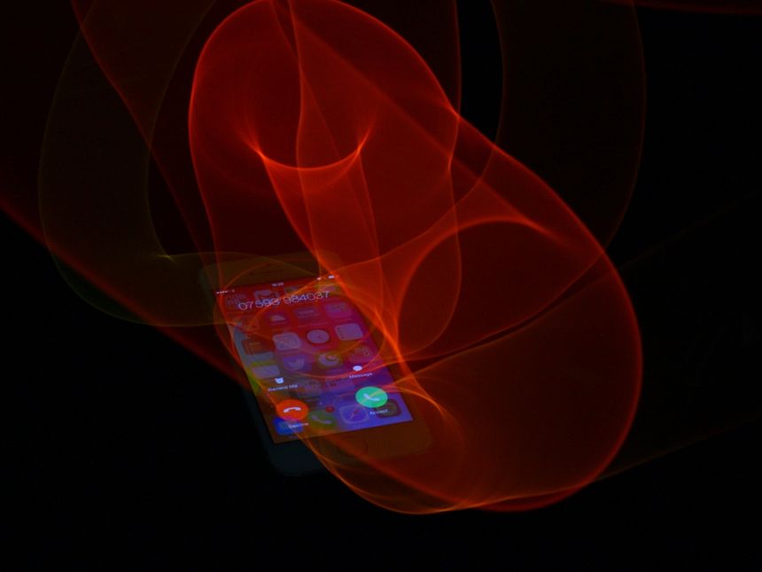A photograph of an iPhone with transparent red light fields all obove it