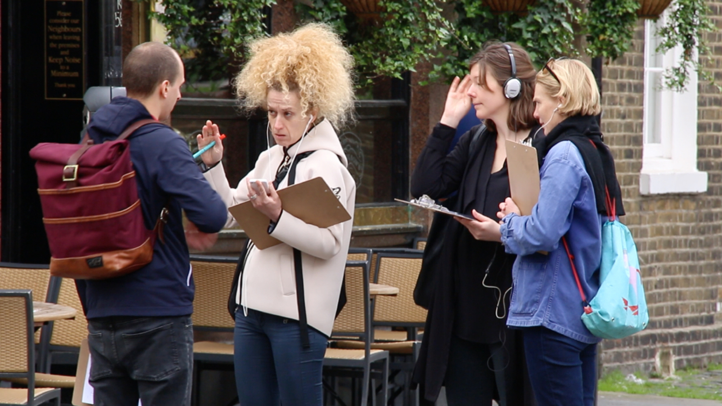 People standing on a street in London listening to a story in their headphones
