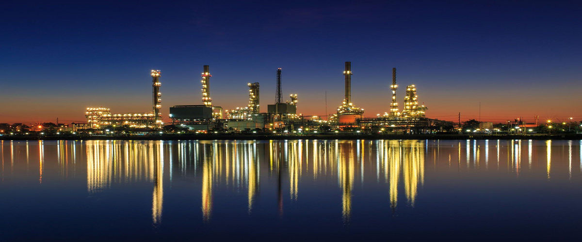 An oil and gas refinery shown next to a sea.