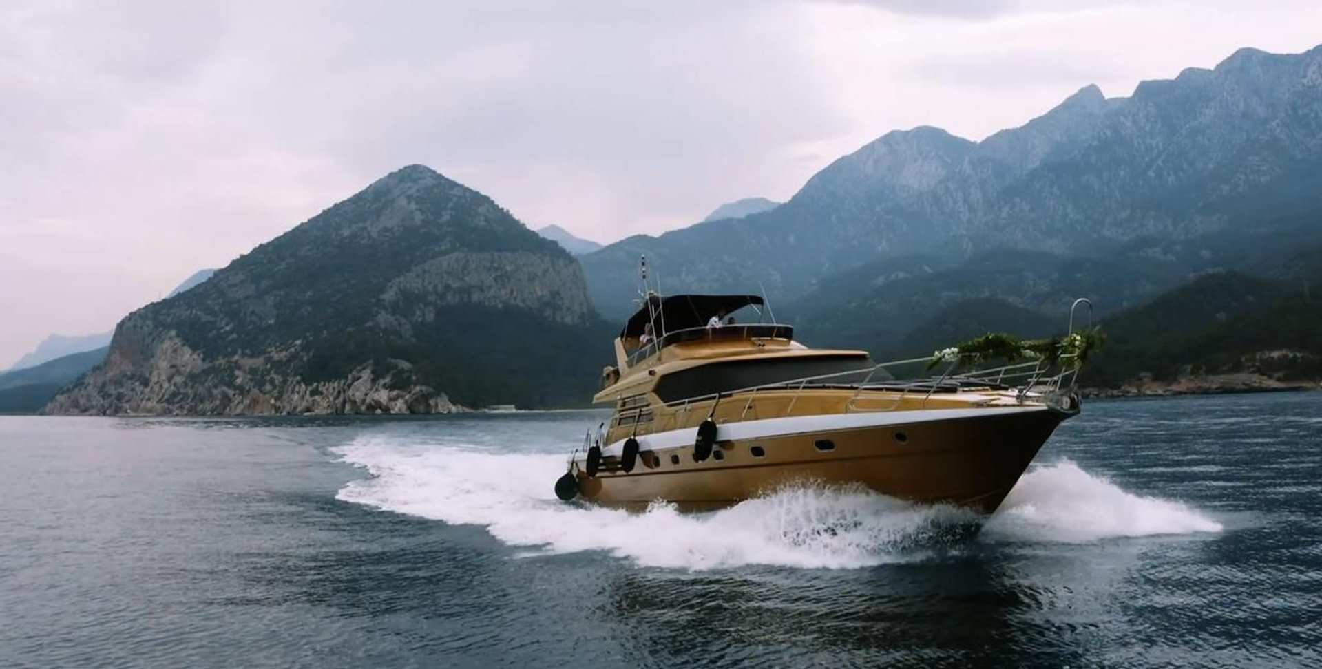 Regnum Yacht cruising on the water with mountainous coast in the background
