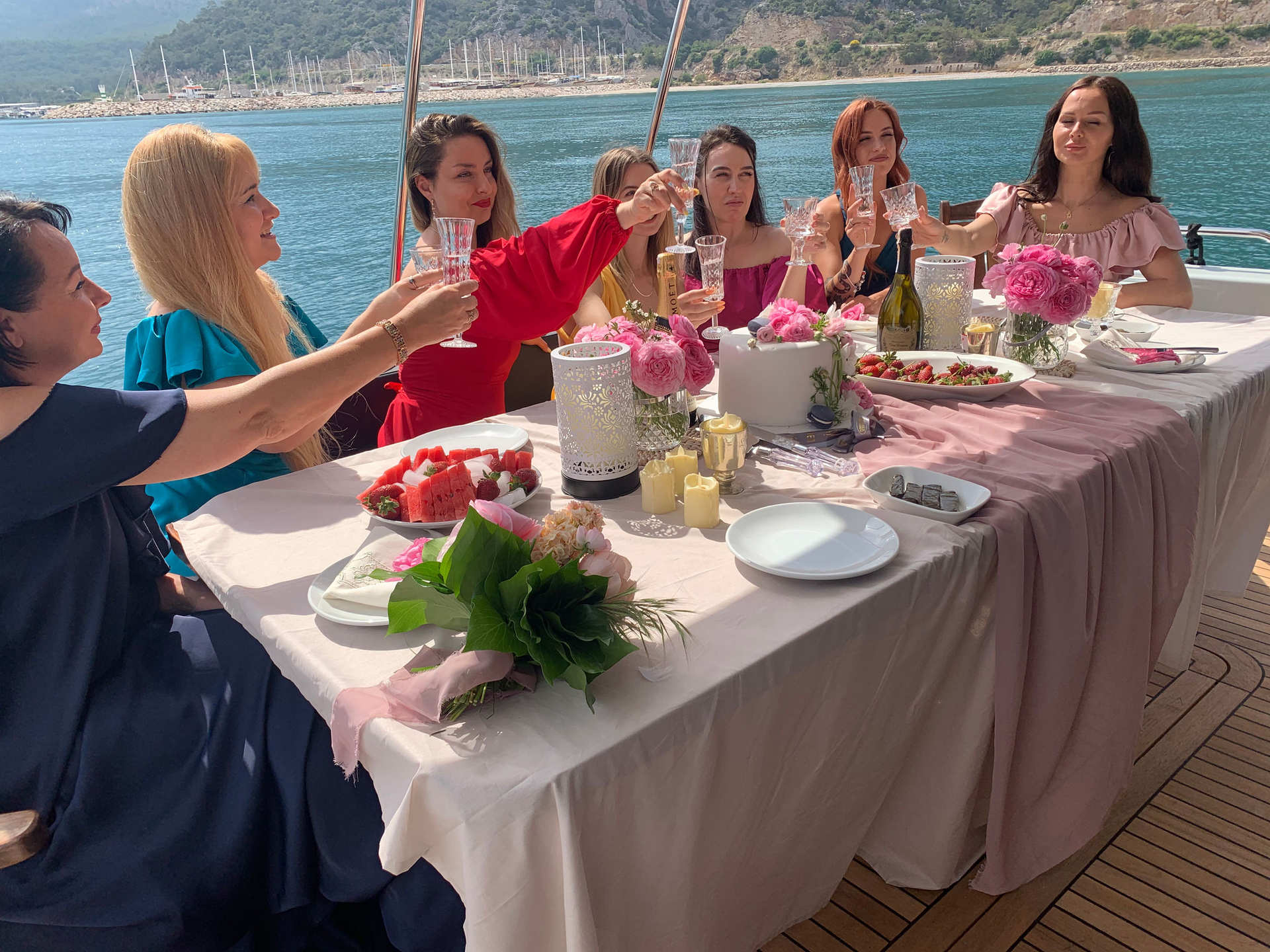 Group of women toasting with glasses around a decorated table on the deck of Regnum Yacht Tour Antalya Private Charter E