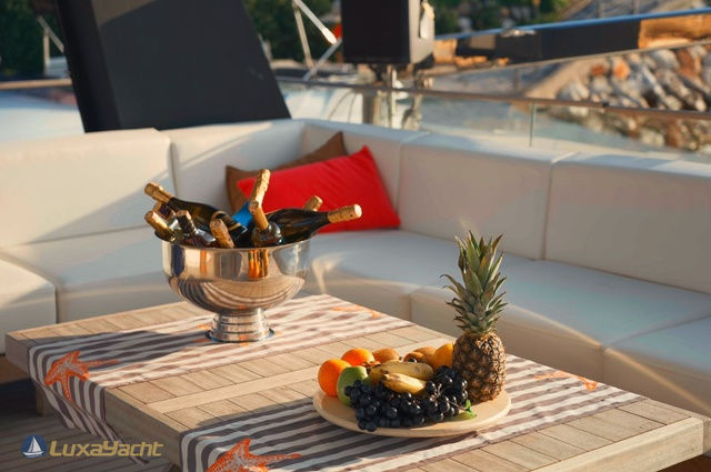 Outdoor seating area with champagne bottles and fruit on a table aboard Brise Yacht