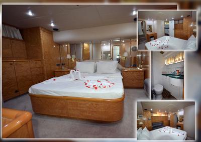 Interior cabin of the Regnum Yacht featuring a large bed with white linens and rose petals, wooden cabinetry, and a bath