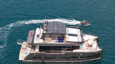 Aerial view of Brise Yacht sailing on clear blue water with a person on a jet ski nearby
