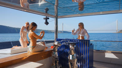 Three women relaxing and enjoying drinks on the deck of Brise Yacht with sea and bridge in background