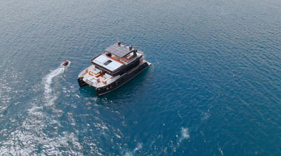 Brise Yacht catamaran cruising on clear blue water with a small boat nearby