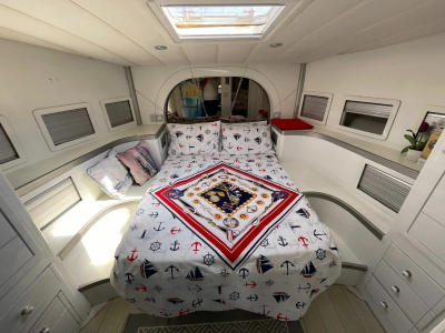Interior cabin with double bed on Ata 36 yacht, featuring nautical-themed bedding and skylight.