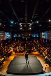 Speaker on stage in front of a seated crowd