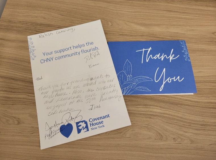 A thank-you card from Covenant House New York with handwritten messages, placed on a wooden surface.