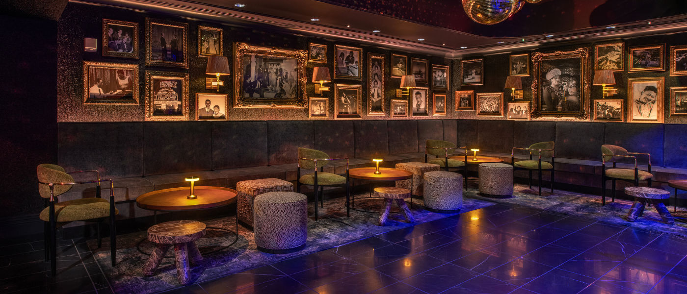 Chic lounge with eclectic wall art, low tables, velvet chairs, and warm ambient lighting.
