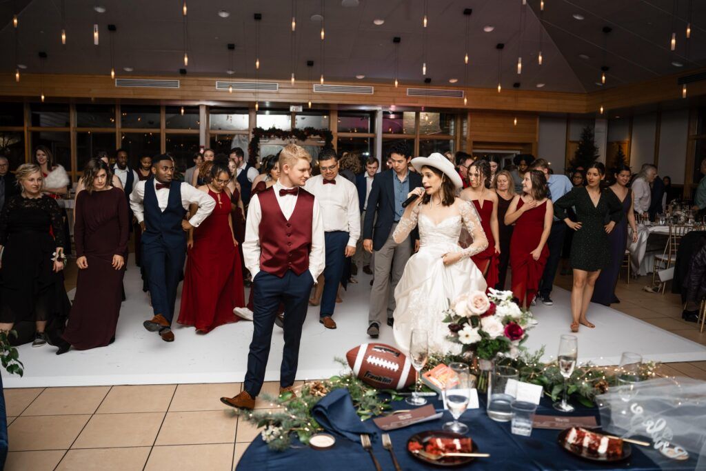 Newlyweds line dancing with guests at reception.