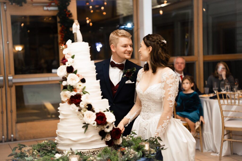Newlyweds cutting cake looking at each other.