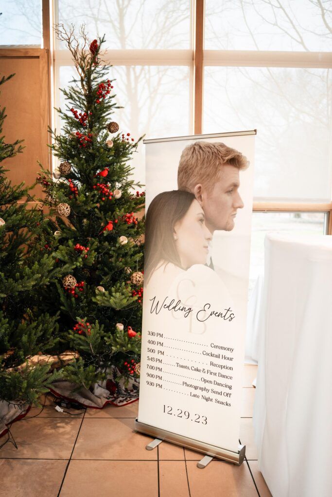 Itinerary sign with couples photo infront of a christmas tree.