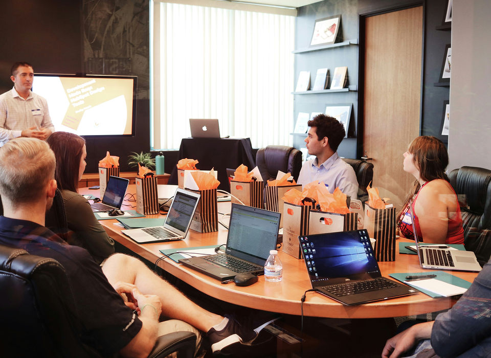 People eating lunch at conference table with laptops