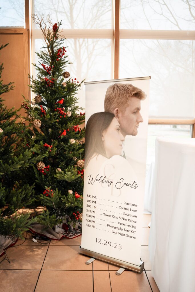 Itinerary sign with couples photo infront of a christmas tree.