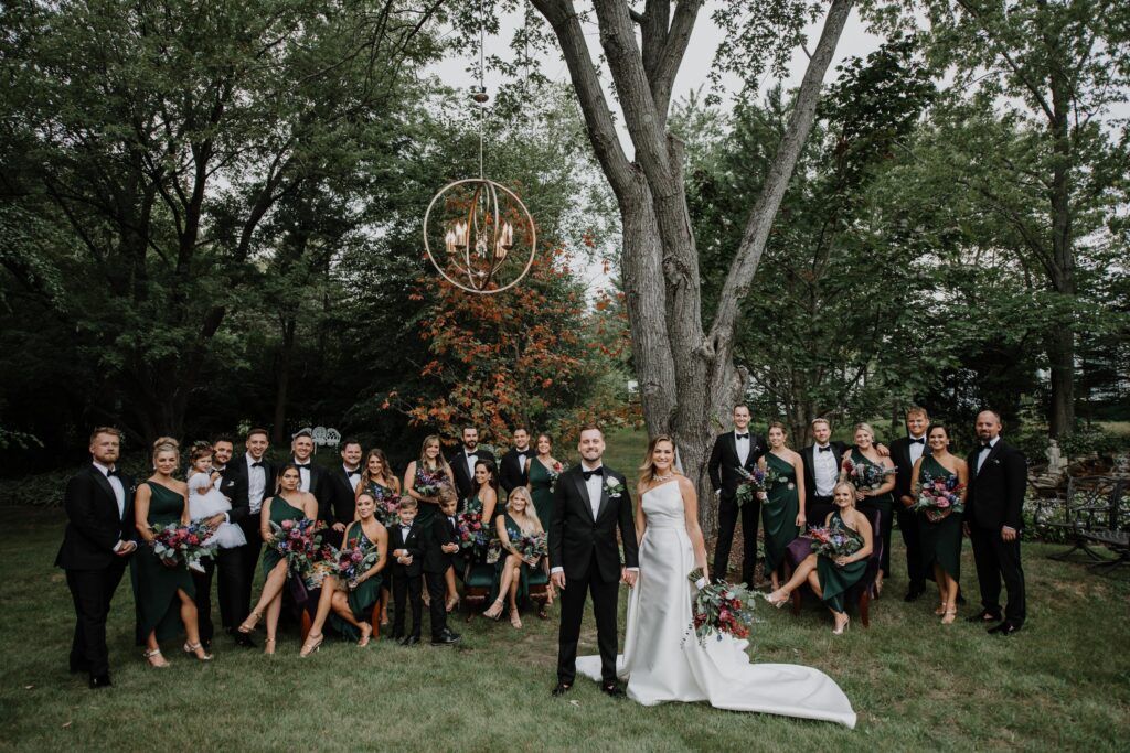 Couple with bridal party under the trees.