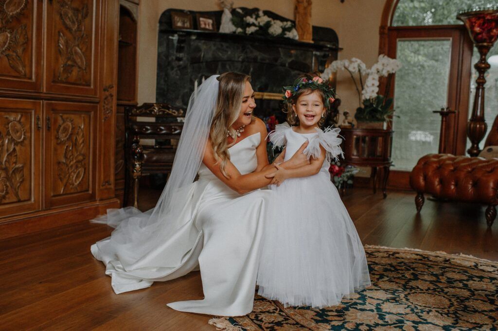 Bride and flower girl laughing.