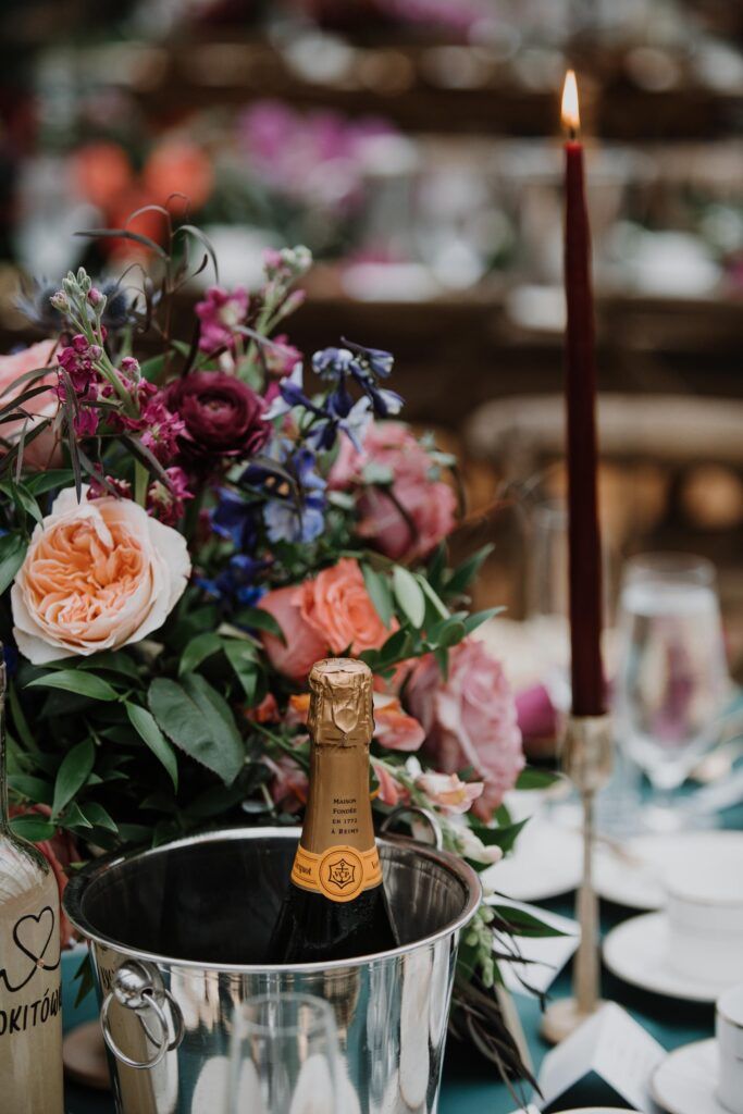Champagne in a bucket in front of floral.
