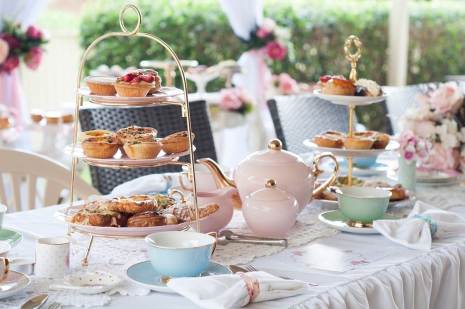 Table with white tablecloth set with pastries and pastel plateware