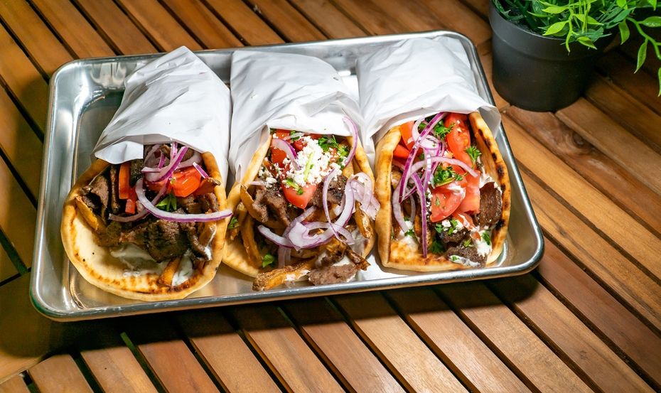 Greek gyros wrapped in foil on a tray on a wooden table