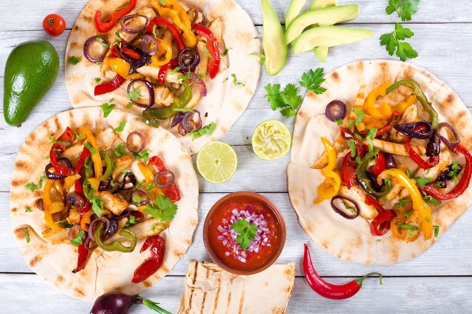 Three chicken fajita tortillas on a grey table