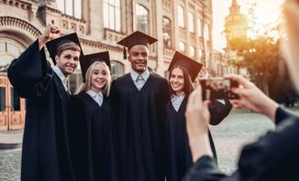 College kids in caps and gowns taking photo after graduation