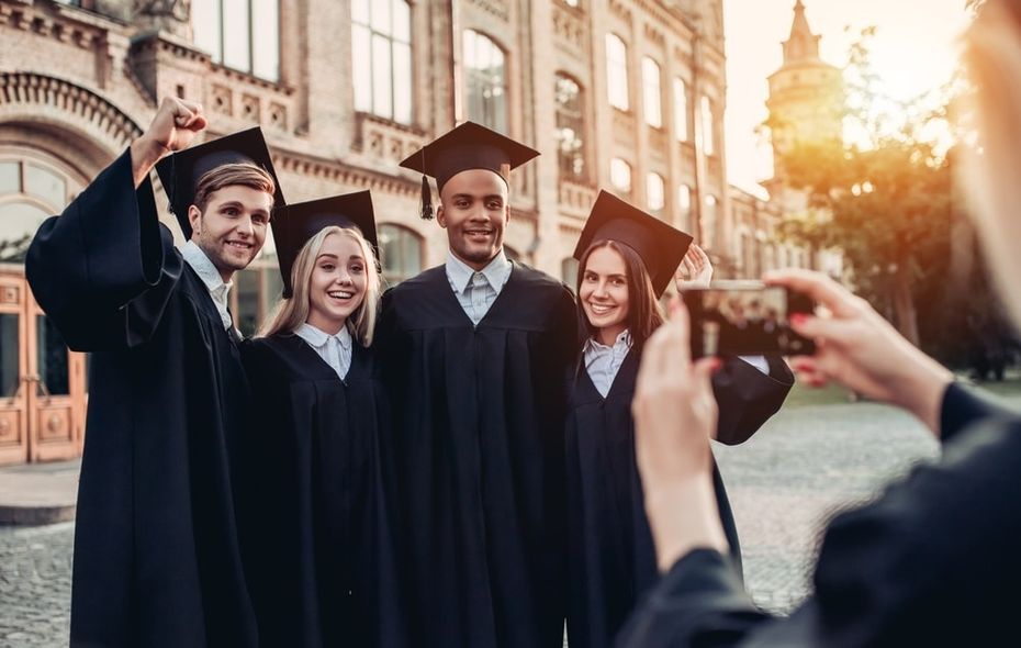 College kids in caps and gowns taking photo after graduation