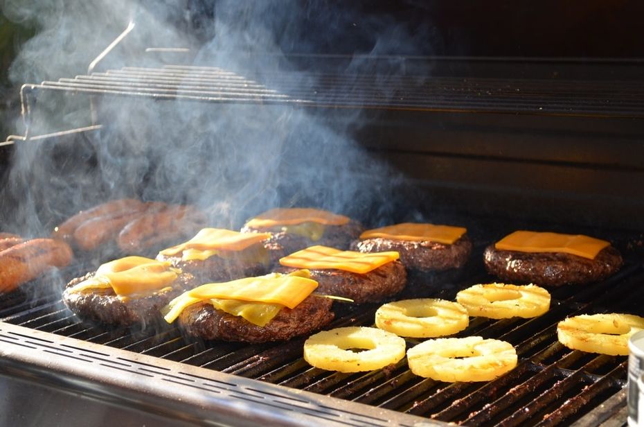 Hot dogs, cheeseburgers and pineapple slices on a grill