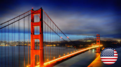 The Golden Gate Bridge illuminated at dusk, with an American flag icon in the lower right corner, captures a perfect moment for travelers dreaming of exploring on an American วีซ่าท่องเที่ยว.
