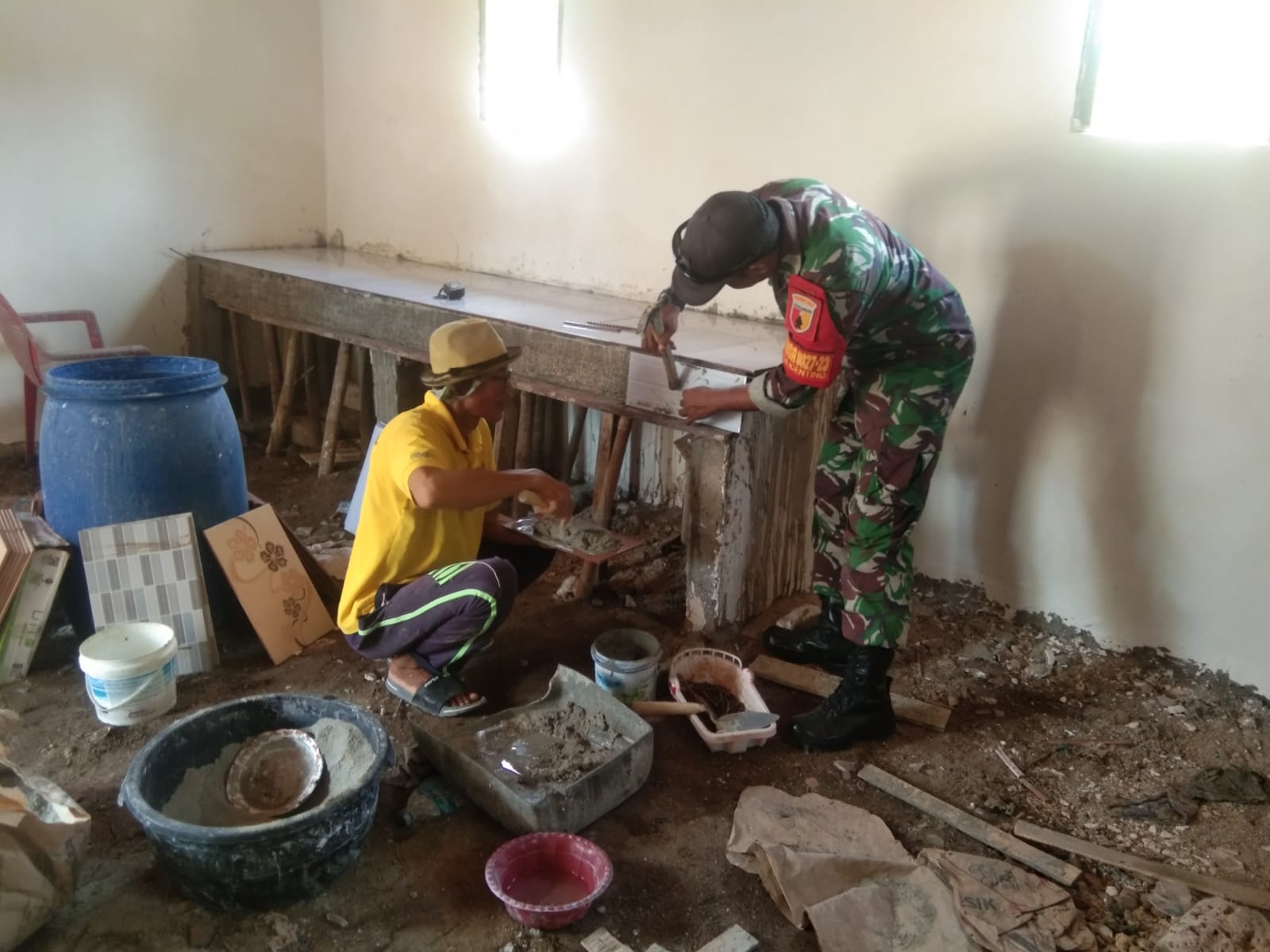 Babinsa Bantu Tukang Pasang Keramik  Lancarkan Komsos Bersama Warganya