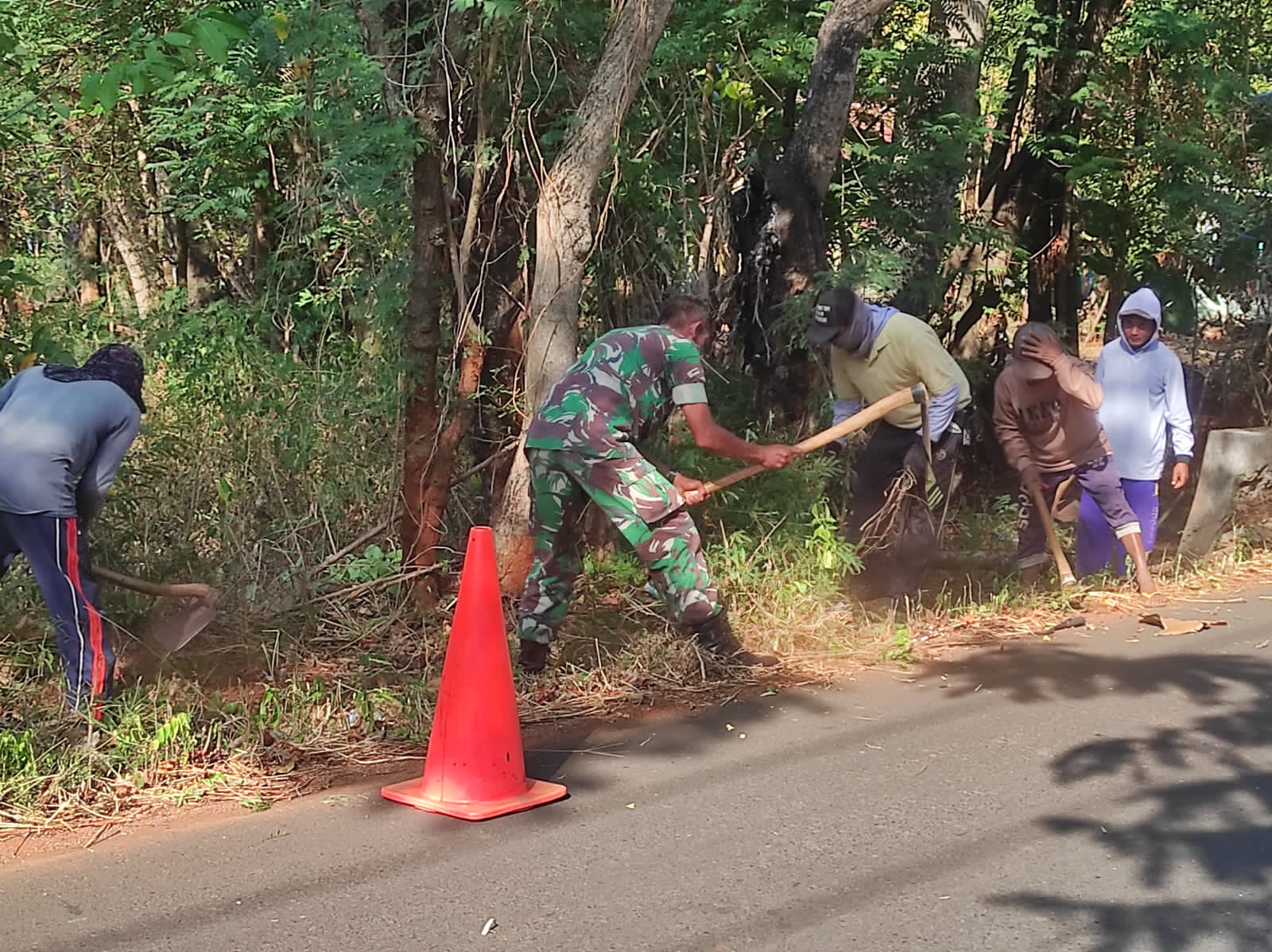 Ajak Warga Binaan, Babinsa Koramil 17/Dungkek Gotong Royong Bersihkan Rumput Dibahu Jalan