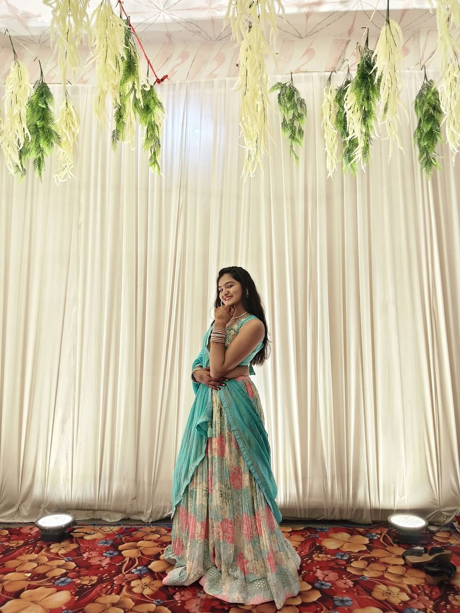 Model at a wedding venue in a pastel floral lehenga with an aqua blouse and aqua dupatta