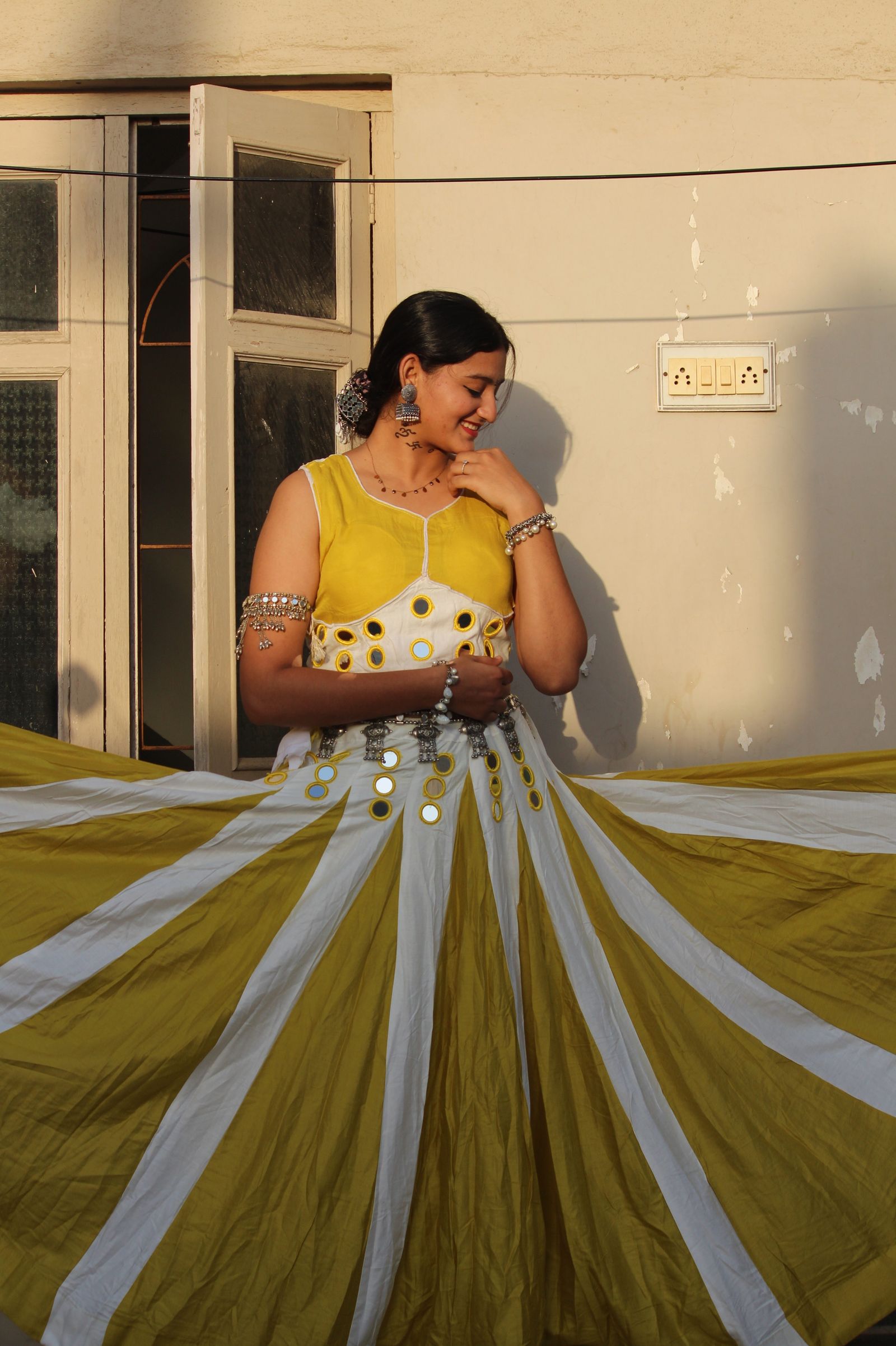 Model twirling in a yellow and white panelled chaniya choli that opens like a sunflower, with a mirror-work blouse