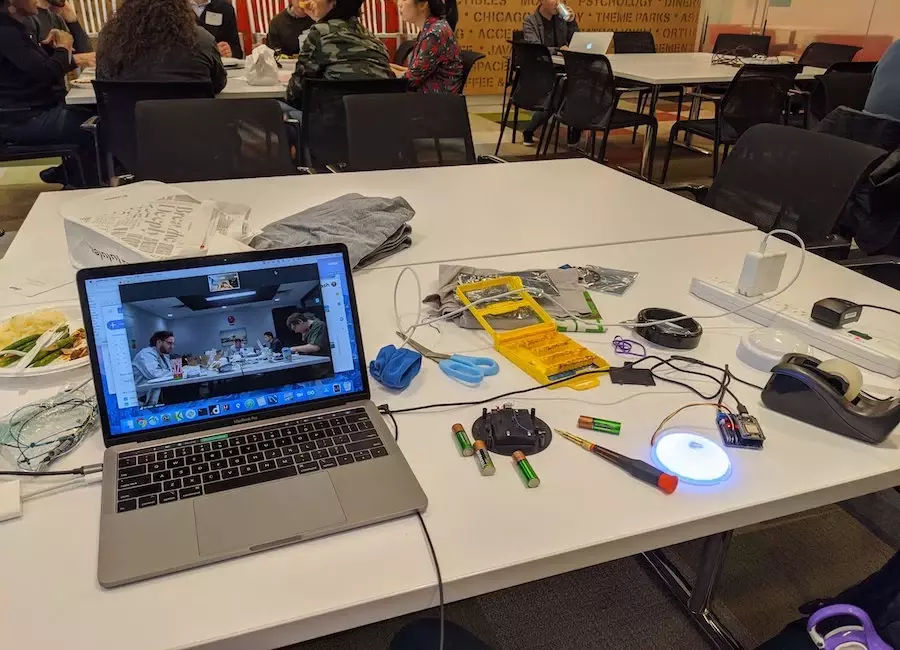 A laptop showing a zoom meeting with hardware strewn about