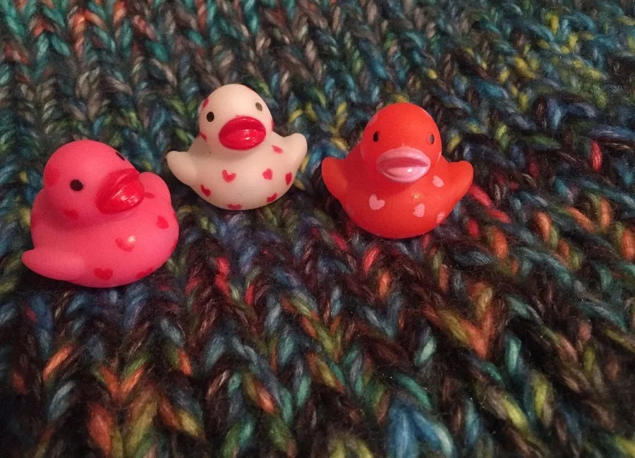 Three rubber ducks sitting on a blanket