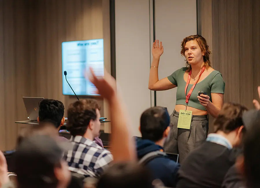 Mandy speaking to a group of students and them raising their hands