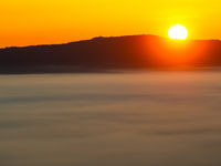 Een ondergaande zon beschijnt een laag wolkendek. © Billy Herman