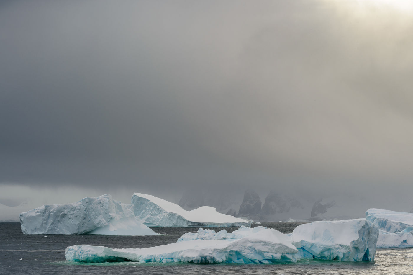 Dreigende wolken hangen boven de ijsbergen en rotsen van Detaille Island. © Bart Heirweg