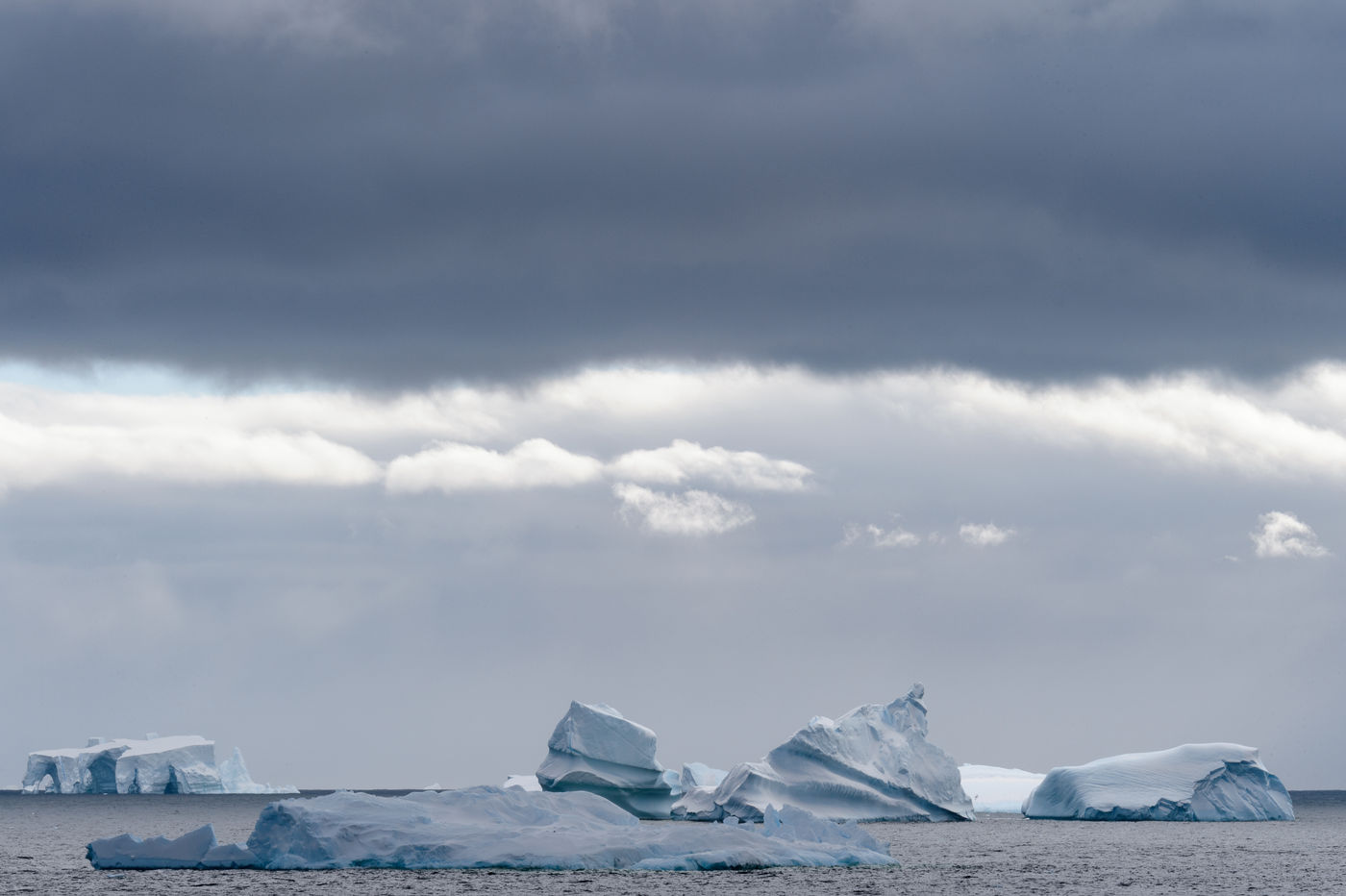 Dreigende wolken hangen boven de ijsbergen en rotsen van Detaille Island. © Bart Heirweg