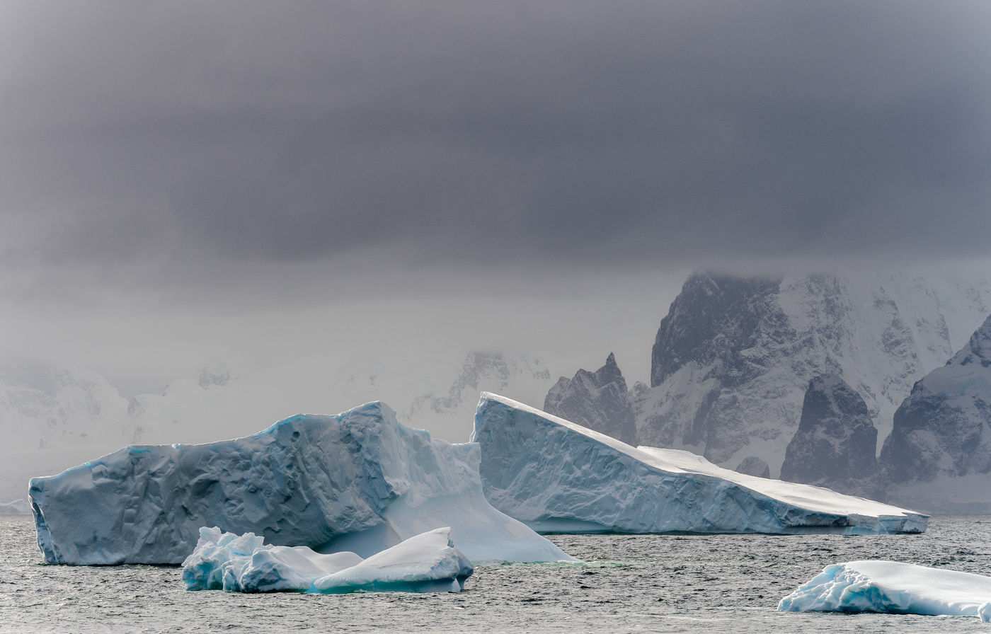 Dreigende wolken hangen boven de ijsbergen en rotsen van Detaille Island. © Bart Heirweg