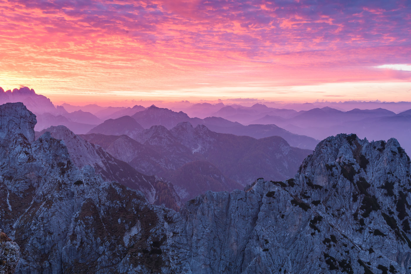 Mistige bergtoppen bij een ondergaande zon. © Bart Heirweg