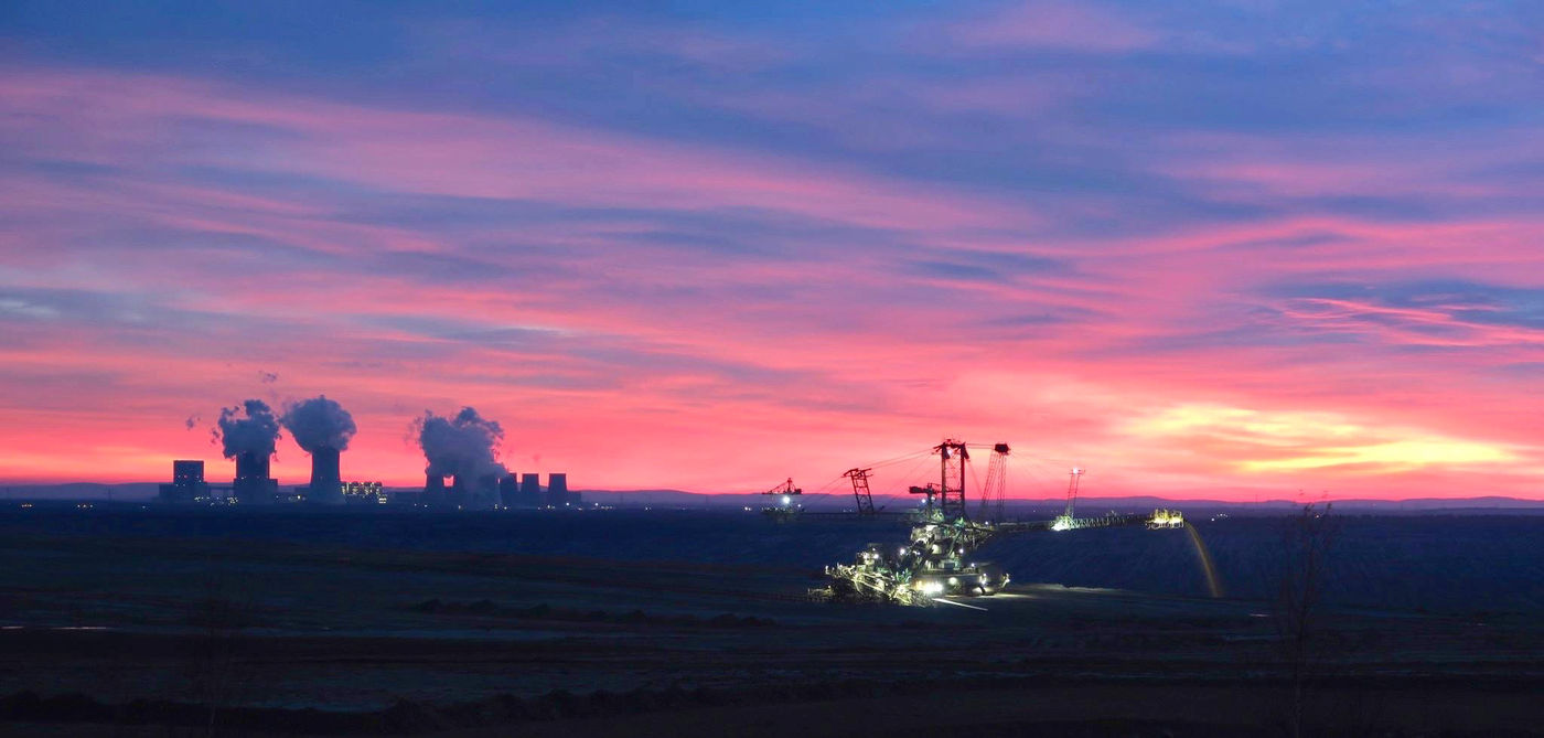 Een sfeerbeeld van de ondergaande zon met industrie op de achtergrond. © Stephan Kaasche