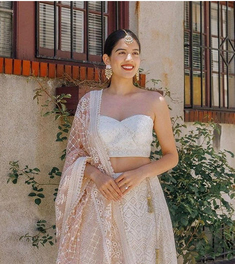 Bride in lehenga smiling near a window